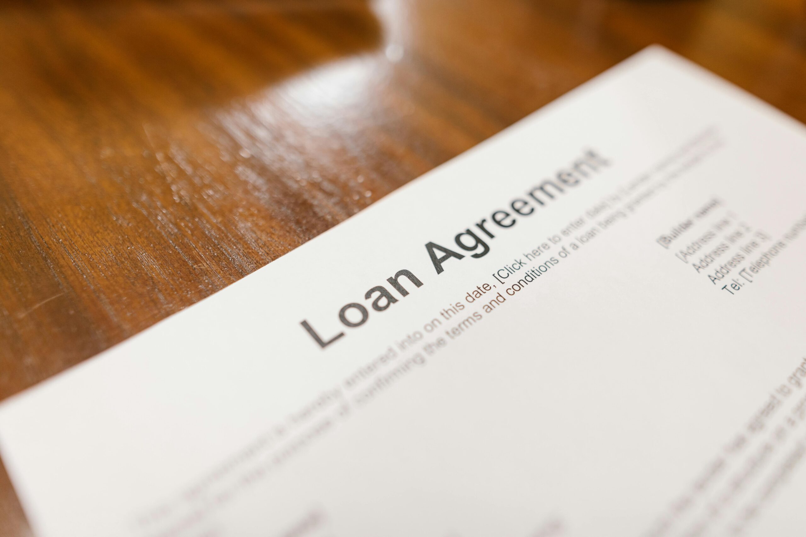 pexels-photo-7841821-7841821 Detailed loan agreement document close-up on a wooden table representing legal and financial concepts.